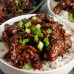 Beef teriyaki over a bowl of rice and sprinkled with green onions.