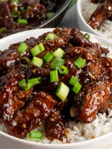 Beef teriyaki over a bowl of rice and sprinkled with green onions.