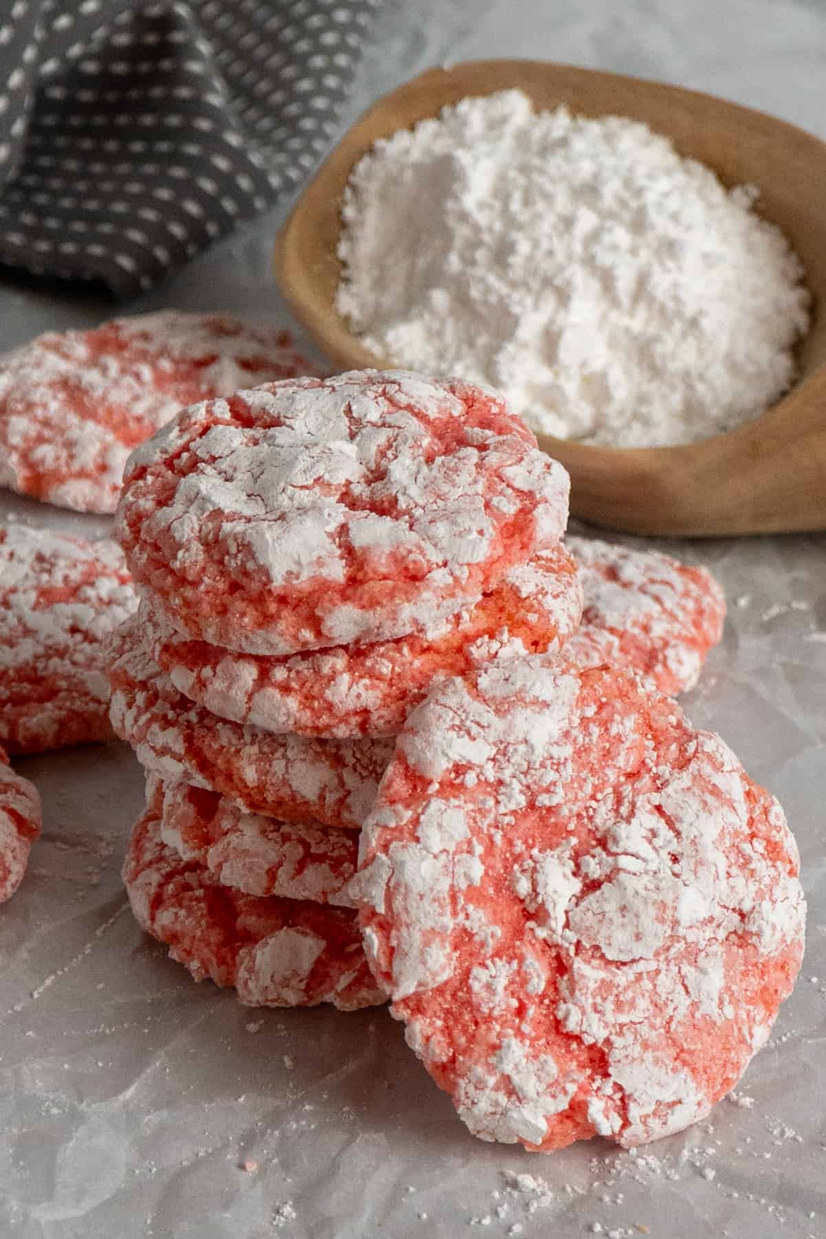 Five pink cookies stacked on top of each other and coated in powdered sugar.