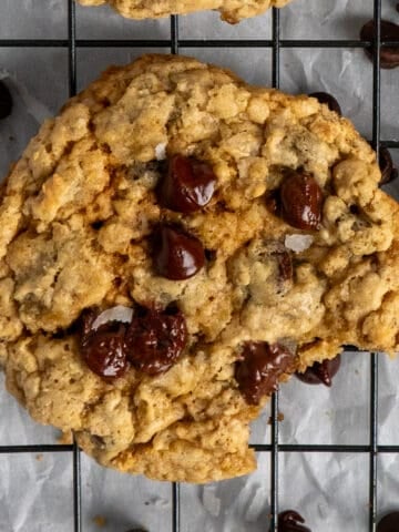 Chocolate chip cookies on a cooling rack with one in the center missing a bite.