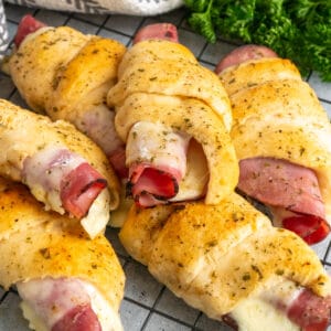 Close-up of ham and cheese crescent rolls on a black cooling rack.