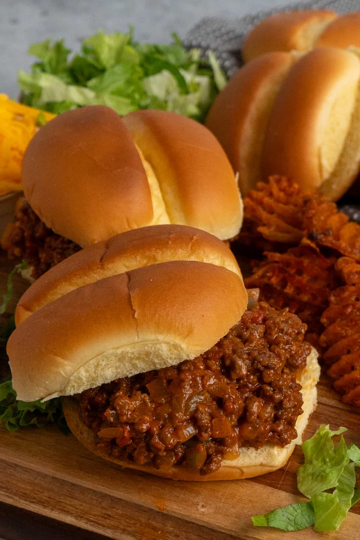 Side view of sloppy Joes on a wood cutting board.