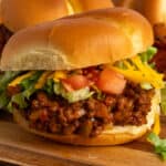 Close up of a taco Joes sandwich on a wood cutting board.