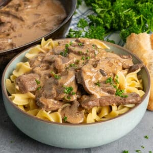 Close-up of beef stroganoff over a bowl of egg noodles.