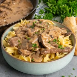 Beef stroganoff over a bowl of egg noodles.