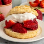 Close up of a strawberry shortcake biscuit on a white plate.