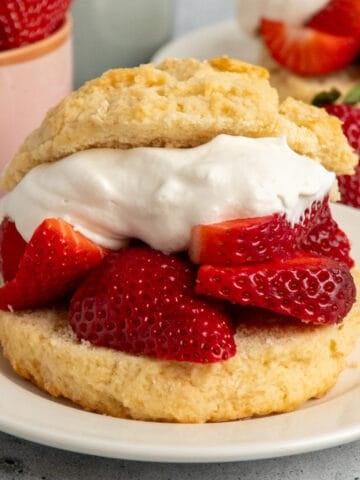 Close up of a strawberry shortcake biscuit on a white plate.