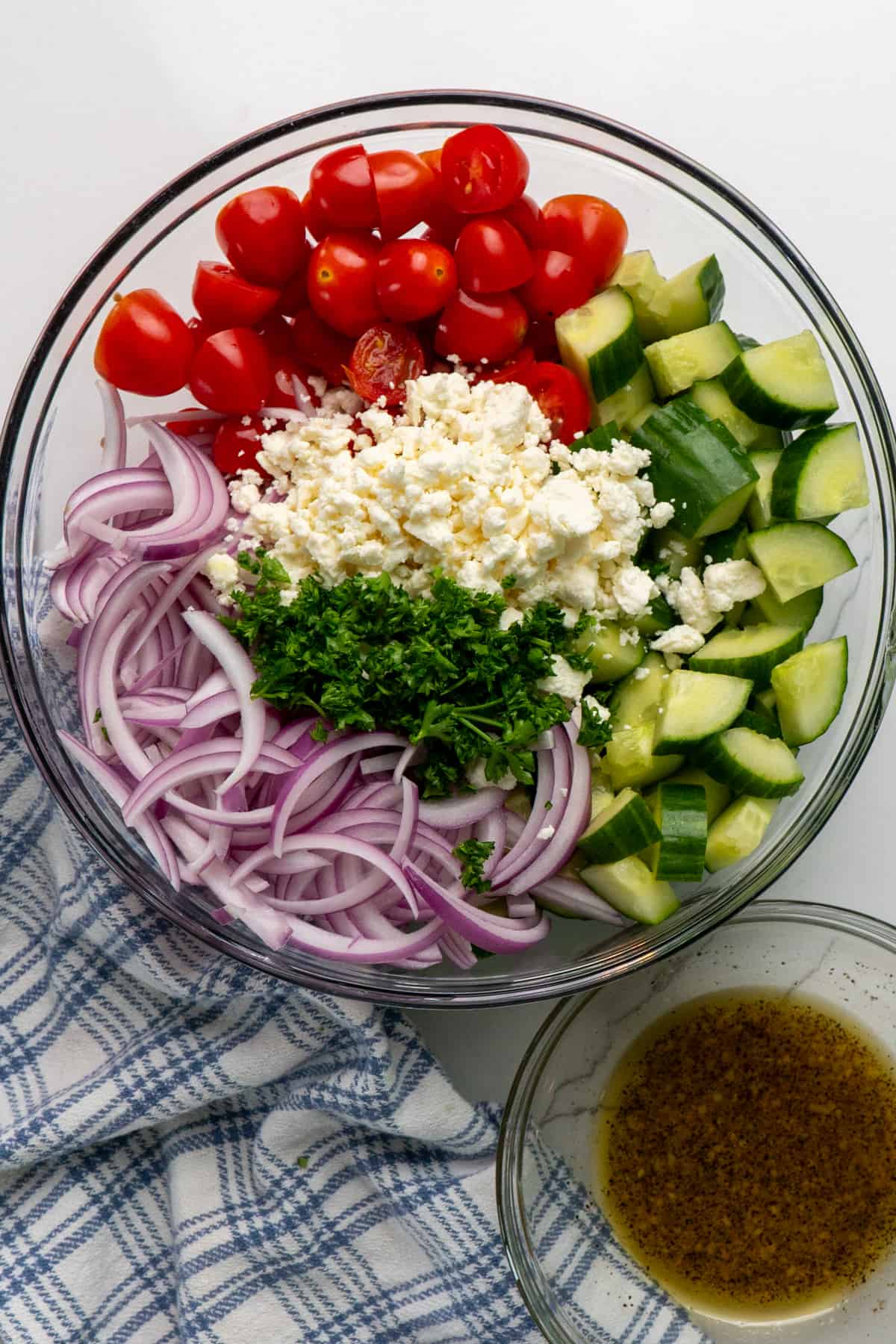 Fresh chopped vegetables and feta cheese in a clear bowl.