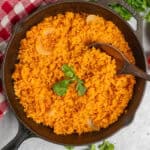 Overhead look at Mexican rice in a skillet with a wooden spoon.