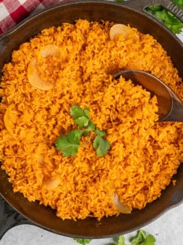 Overhead look at Mexican rice in a skillet with a wooden spoon.