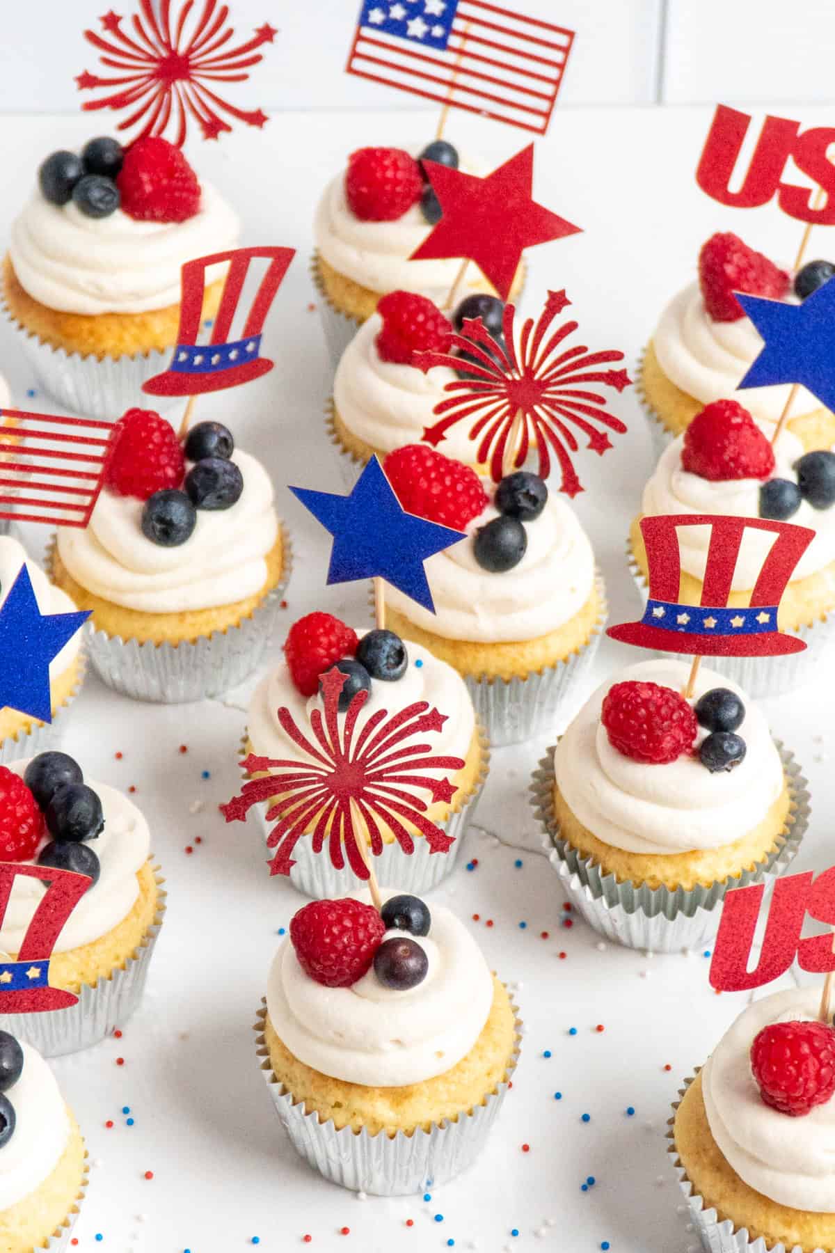 Overhead look at cupcakes with raspberries and blueberries on top.