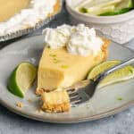 A piece of key lime pie on a plate with a bite take out of it.