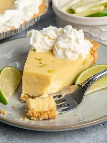 A piece of key lime pie on a plate with a bite take out of it.