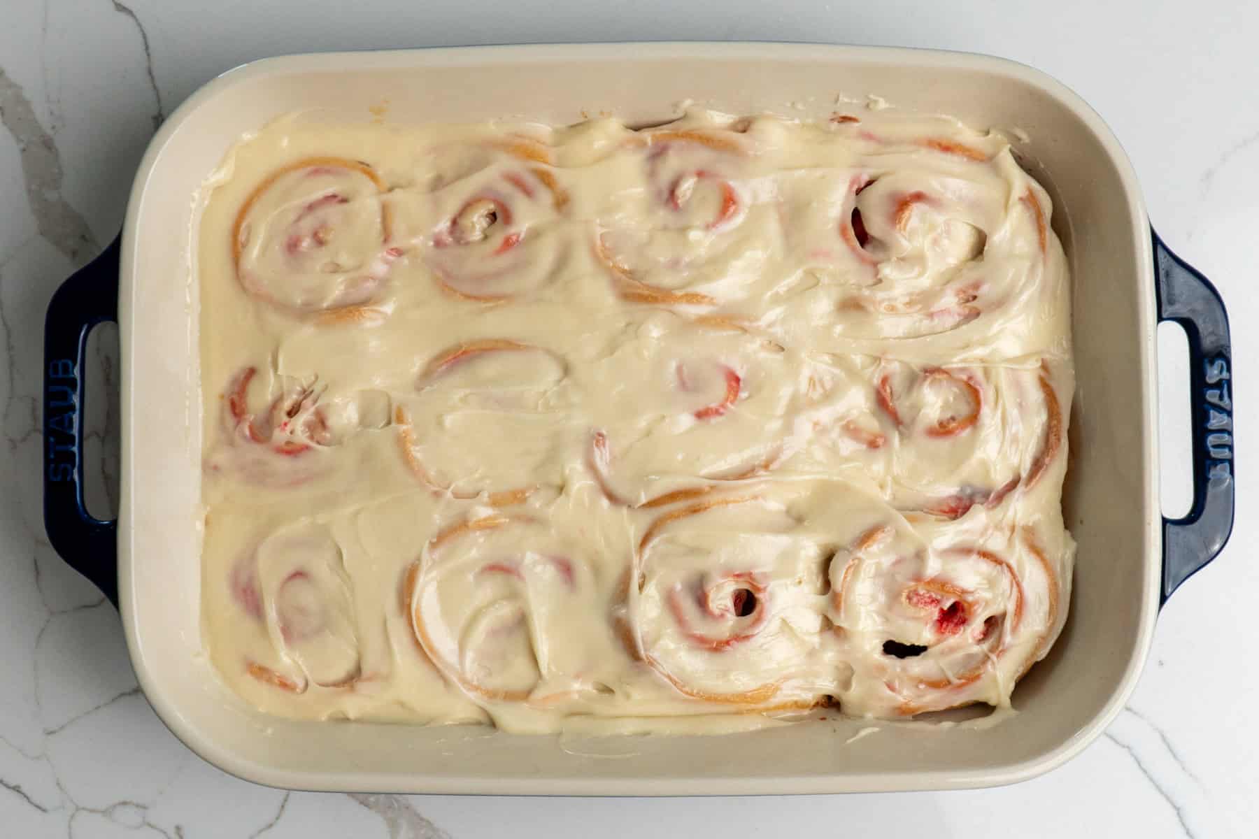 Overhead look at iced cinnamon rolls in a baking dish.
