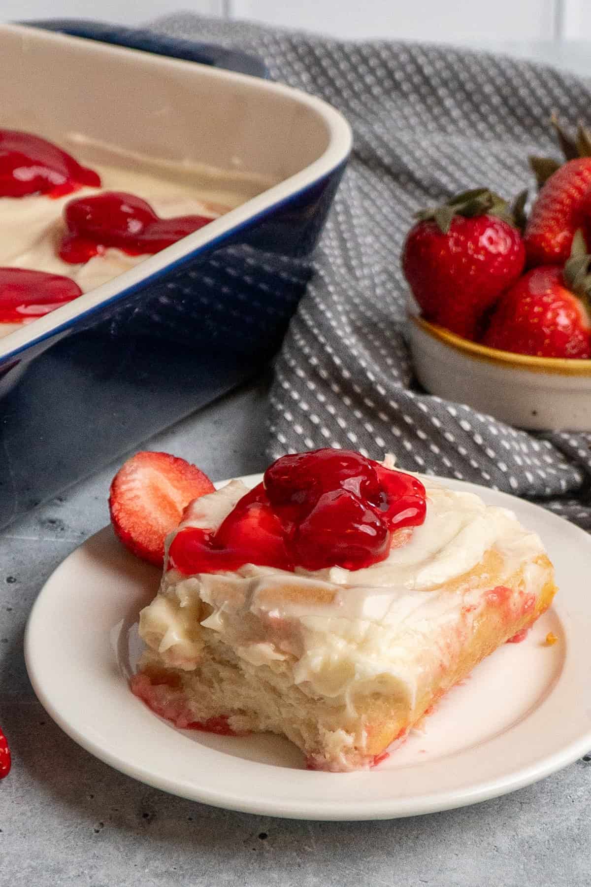 Close up of strawberry cheesecake cinnamon rolls on a white plate.
