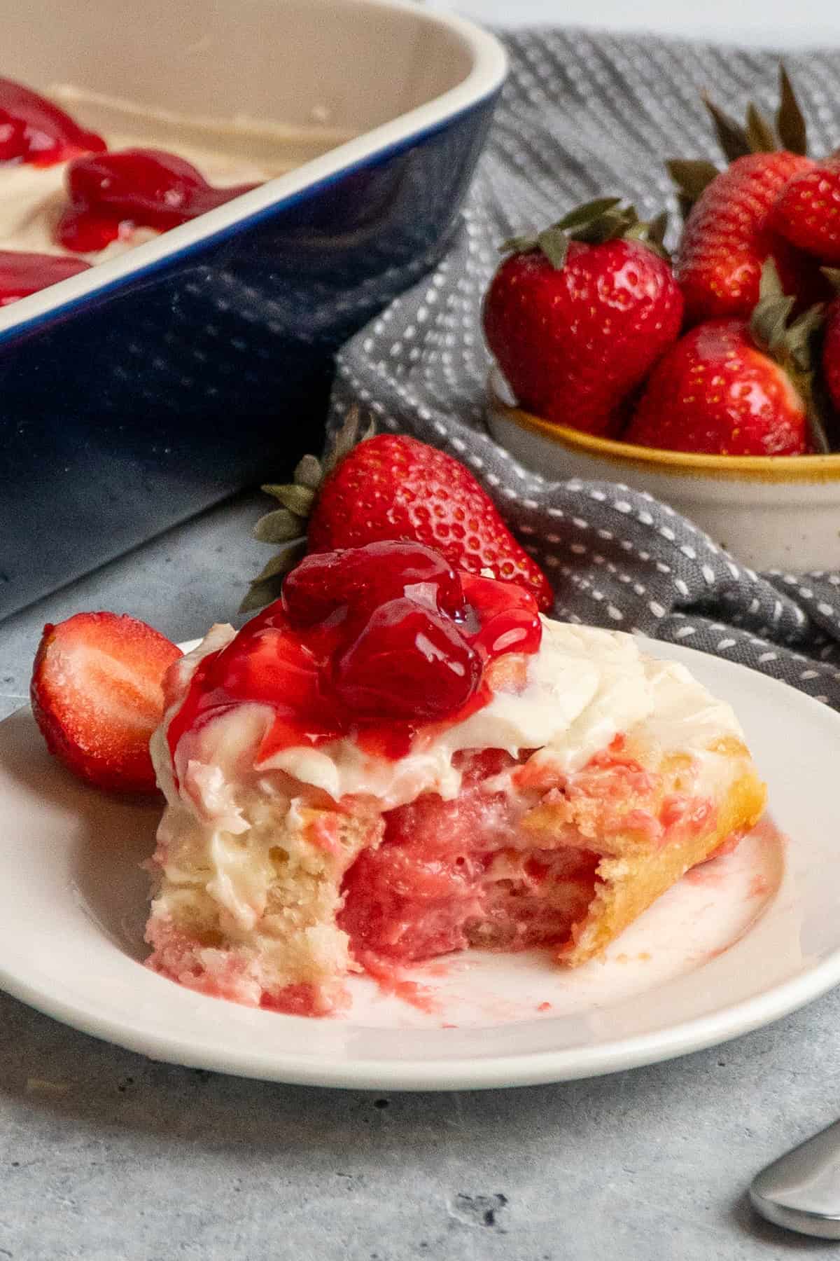Close up of a strawberry cheesecake cinnamon roll with a bite taken out of it.