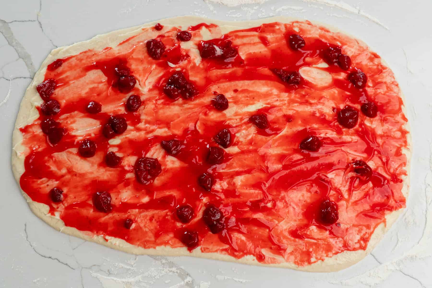Overhead look at cream cheese and strawberry filling on the prepared dough.