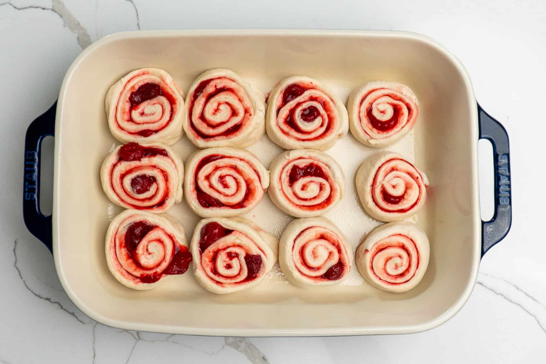 Strawberry cheesecake cinnamon roll in a prepared baking dish.