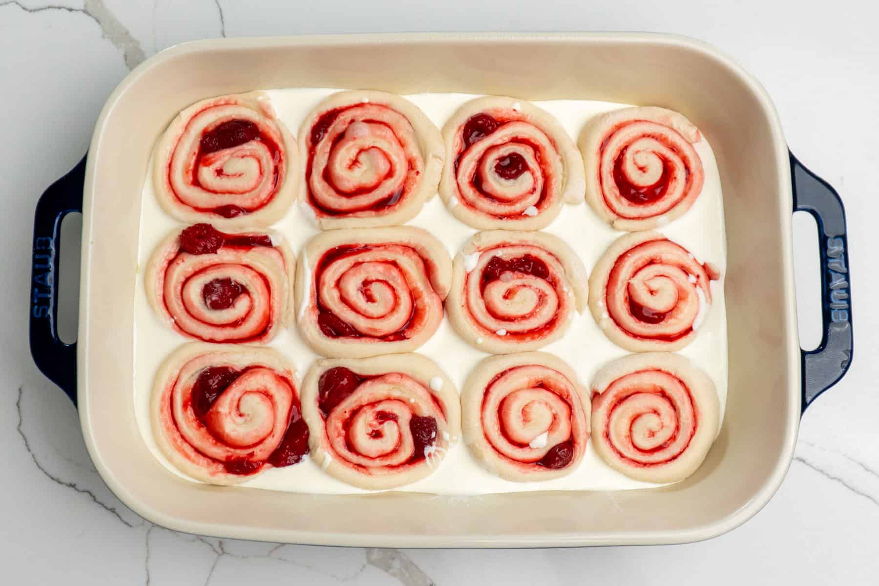 Heavy cream poured around cinnamon rolls.