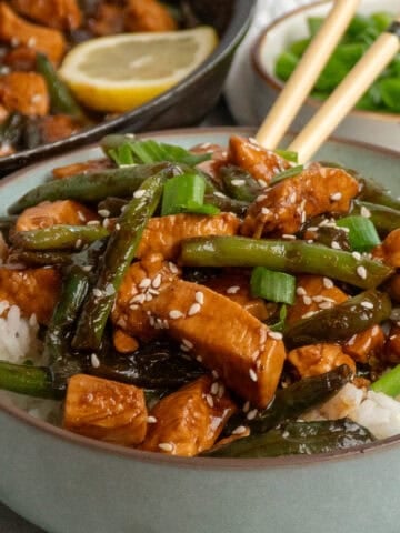 Close up of chicken and green bean stir fry over a bowl of rice.