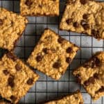Overhead look at oatmeal chocolate chip bars stacked on a black cooling rack.