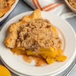 Close up of a slice of peach pie on a white plate.