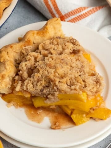Close up of a slice of peach pie on a white plate.