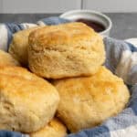 Homemade biscuits stacked up in a bread basket.