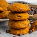 Four pumpkin chocolate chip cookies stacked on top of each other.