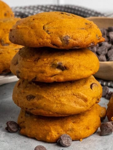 Four pumpkin chocolate chip cookies stacked on top of each other.