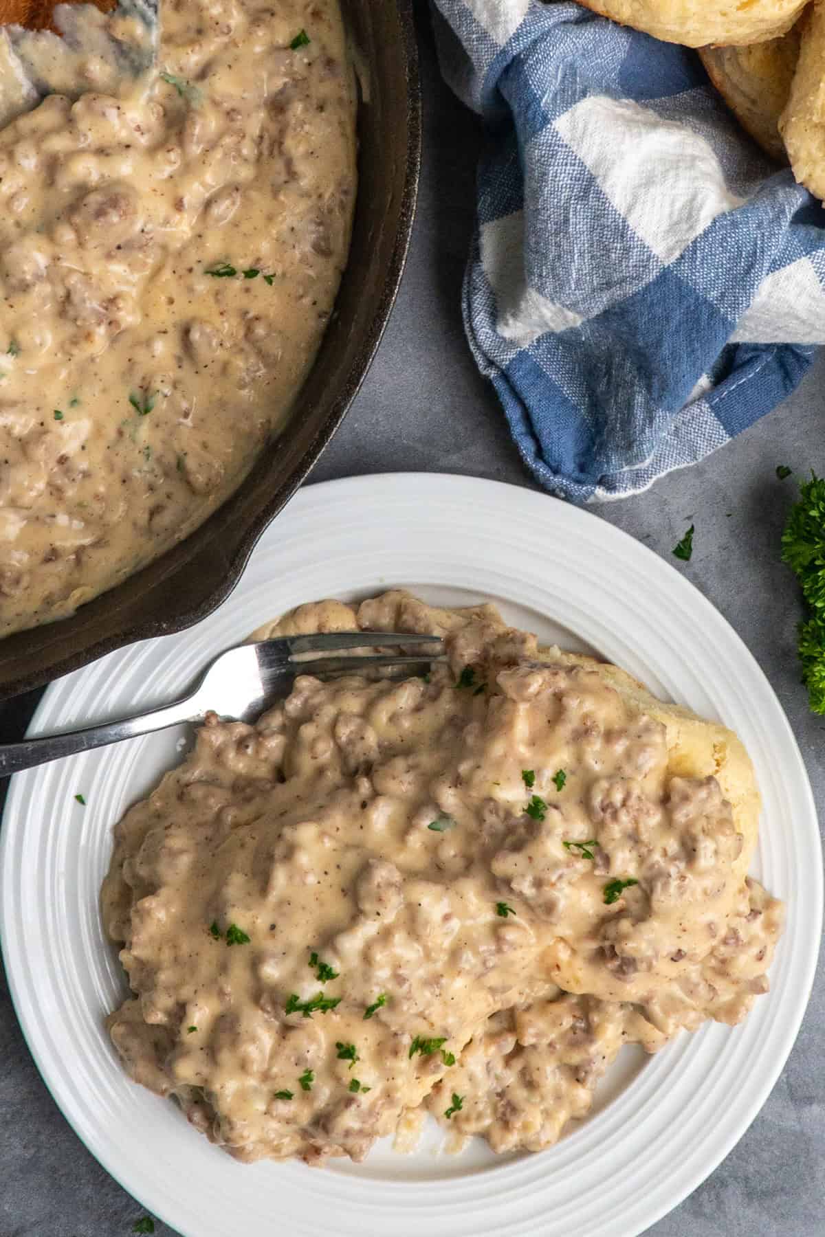 Sausage and gravy over biscuits on a white plate.