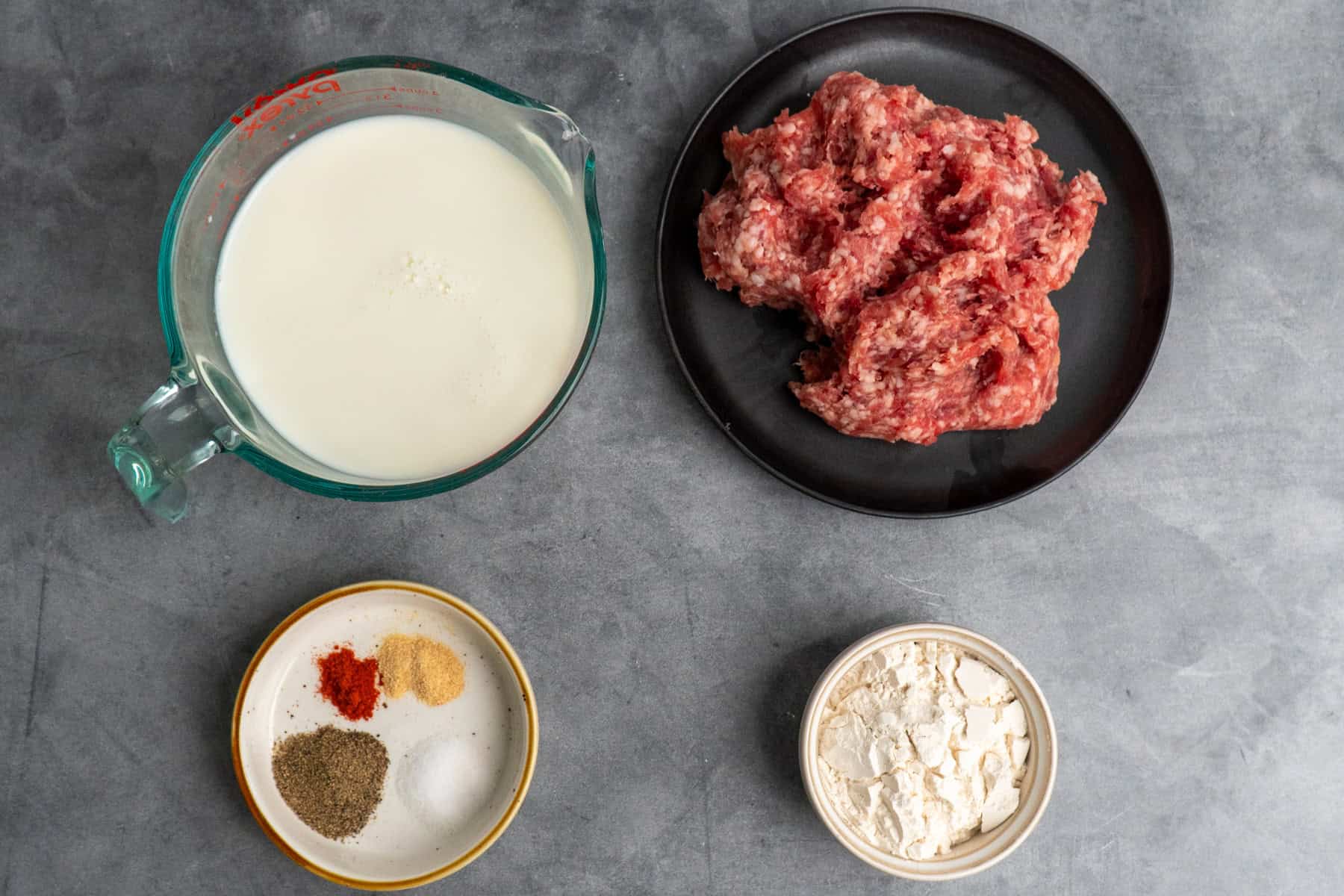 Ingredients for sausage and gravy on a gray background before cooking.