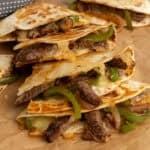 Four steak quesadillas stacked on top of each other ready to be served.