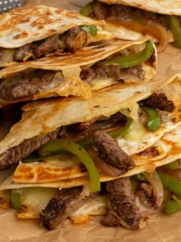 Four steak quesadillas stacked on top of each other ready to be served.