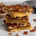 Three pecan pie bars stacked on top of each other.