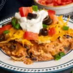 Chicken taco casserole on a plate topped with sour cream and toppings.