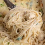 A wooden spoon lifting up a serving of chicken tetrazzini from the casserole dish.