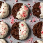 Chocolate peppermint cookies on parchment paper surrounded by crushed candy canes.