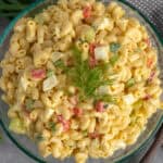 A bowl of devilled egg pasta salad garnished with green onions.