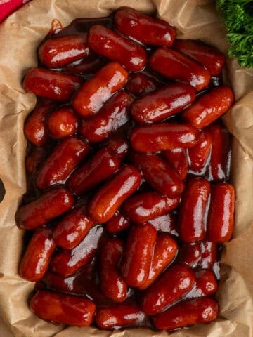 Crock pot little smokies on a tray with parchment paper.