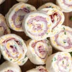 Ham and cheese roll ups stacked on a plate.