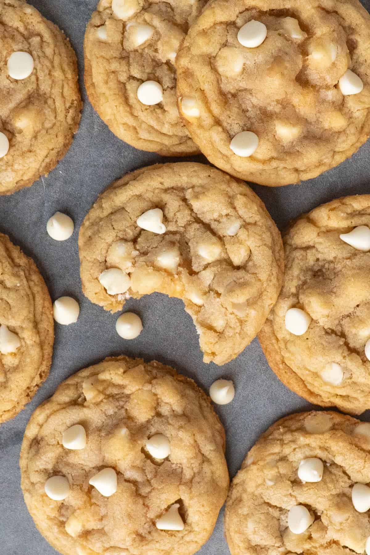 White chocolate & macadamia nut cookies on a counter top with that has a bite taken out of it.