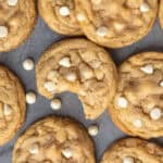 White chocolate & macadamia nut cookies on a counter top with that has a bite taken out of it.