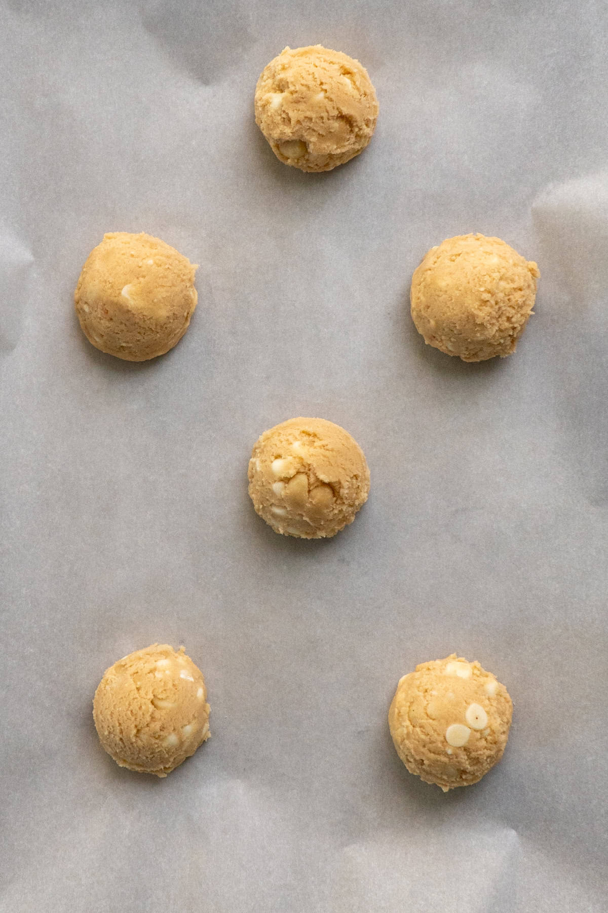 Cookie dough formed into balls and scooped onto a baking sheet.