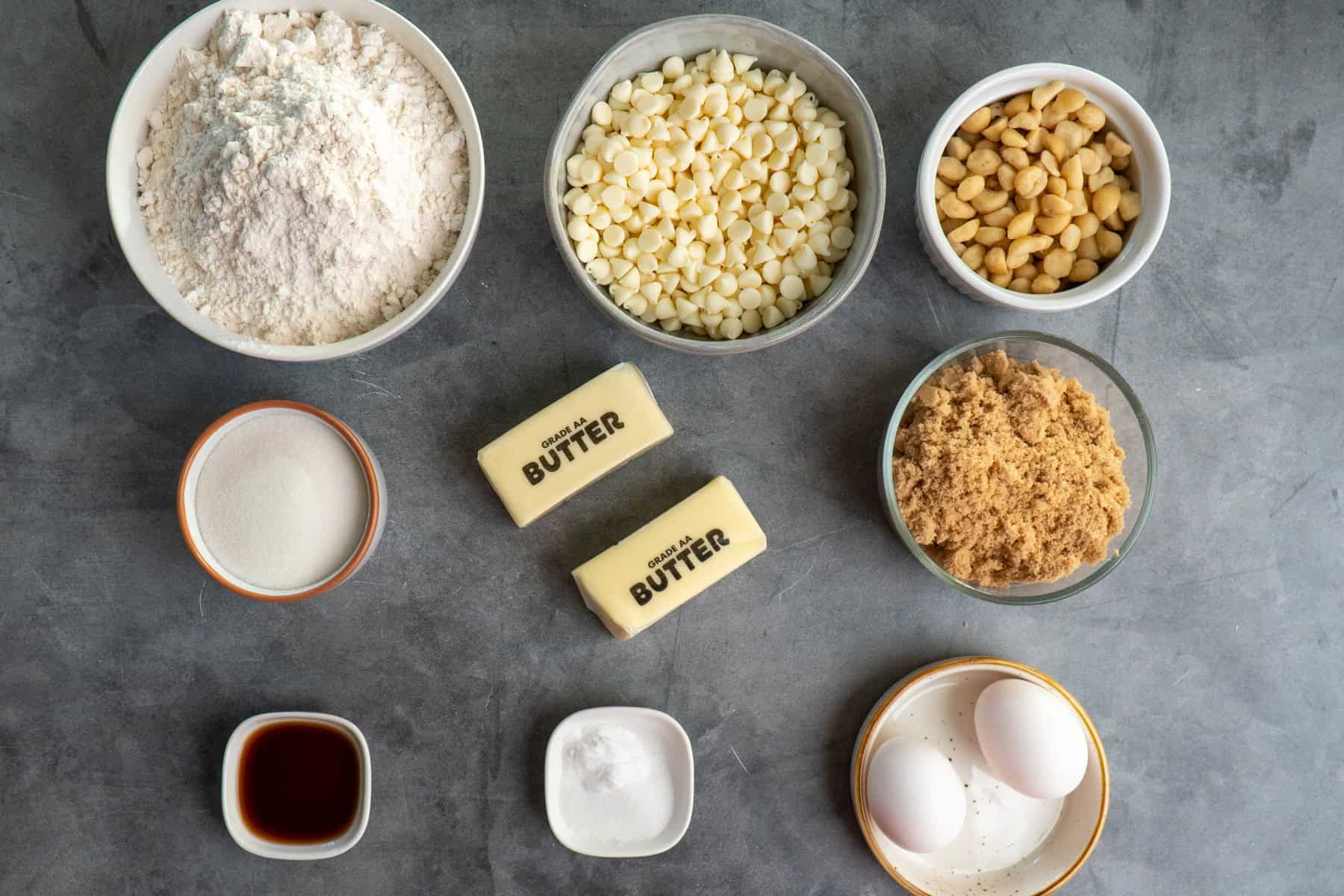 Ingredients to make white chocolate & macadamia nut cookie in bowls.