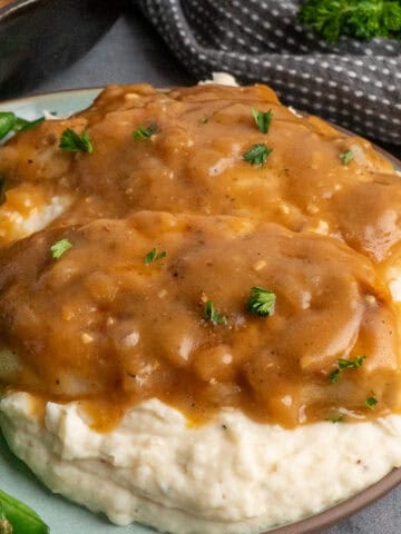 Chicken and gravy over a plate of mashed potatoes.