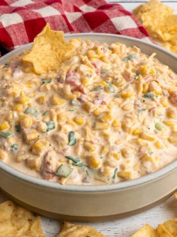 Crack corn dip in a bowl on the table surrounded by corn chips.