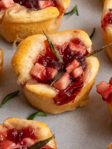 Cranberry brie bites scattered on a piece of parchment.