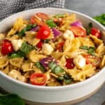 Bruschetta pasta salad in a bowl with a gray dish towel in the background.