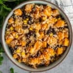 Butternut squash quinoa salad in a bowl with parsley in the background.